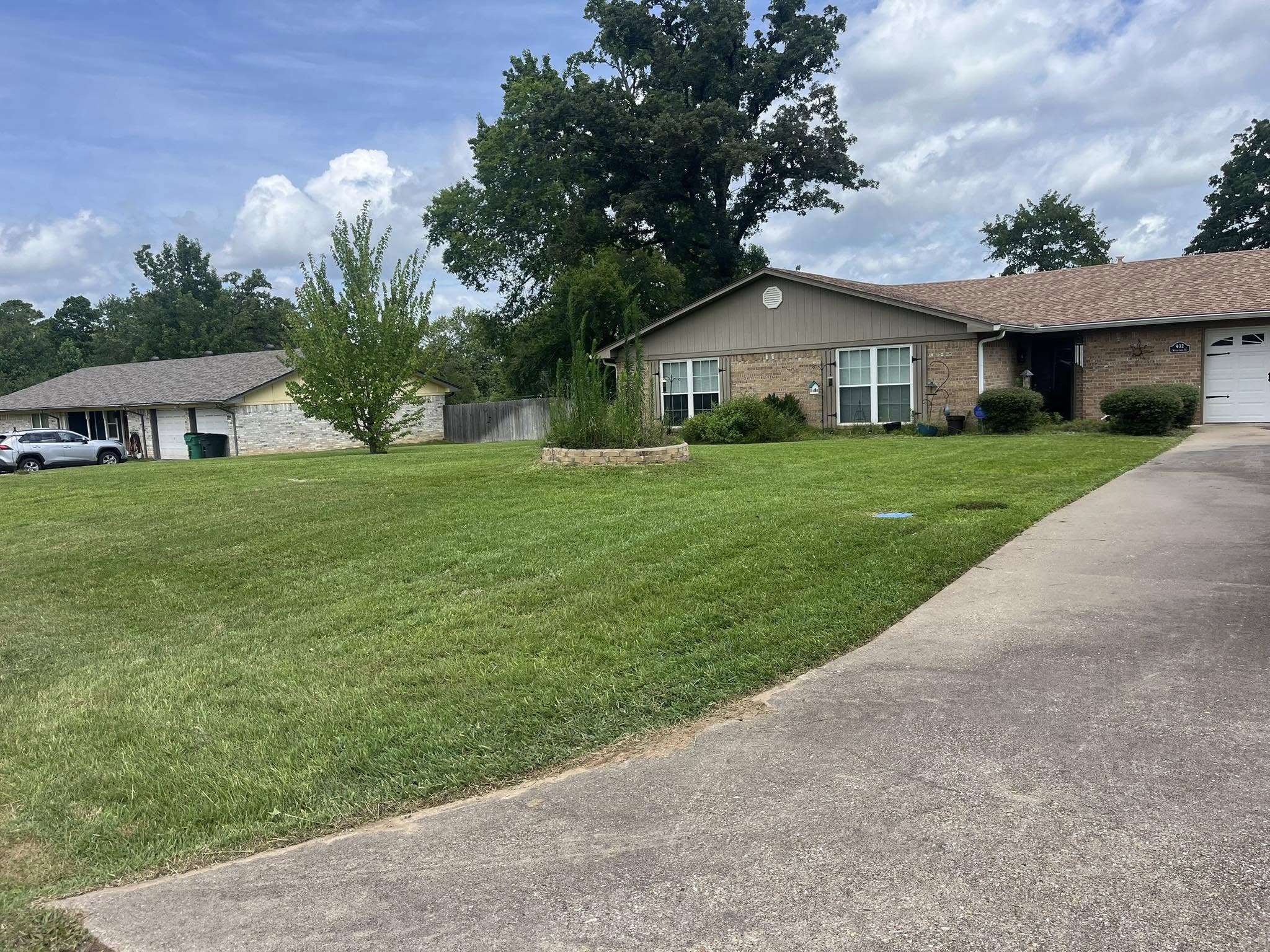 Wide green residential lawn with neat landscaping in front of a brick home